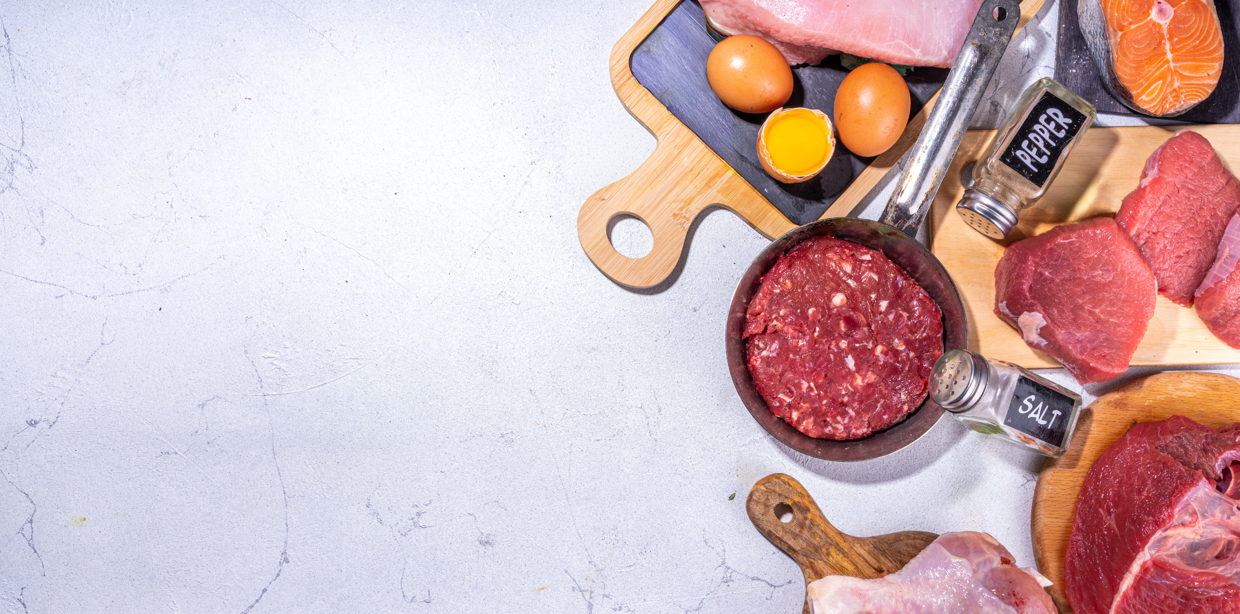 Fleisch, Eier, Fisch, Holzbretter und grauer Hintergrund