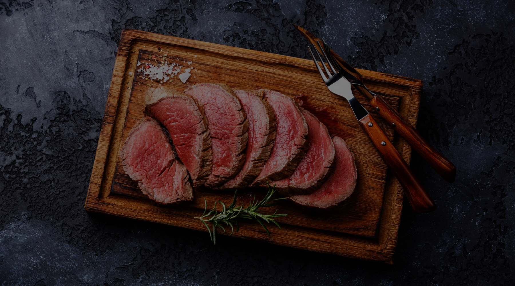 Steak aufgeschnitten auf Holzbrett mit schwarzem Hintergrund